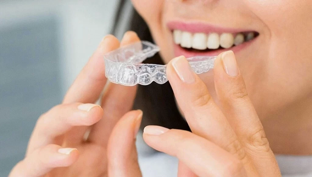 woman smiling while holding invisalign braces