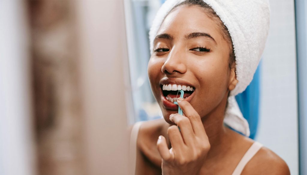 woman flossing in the mirror