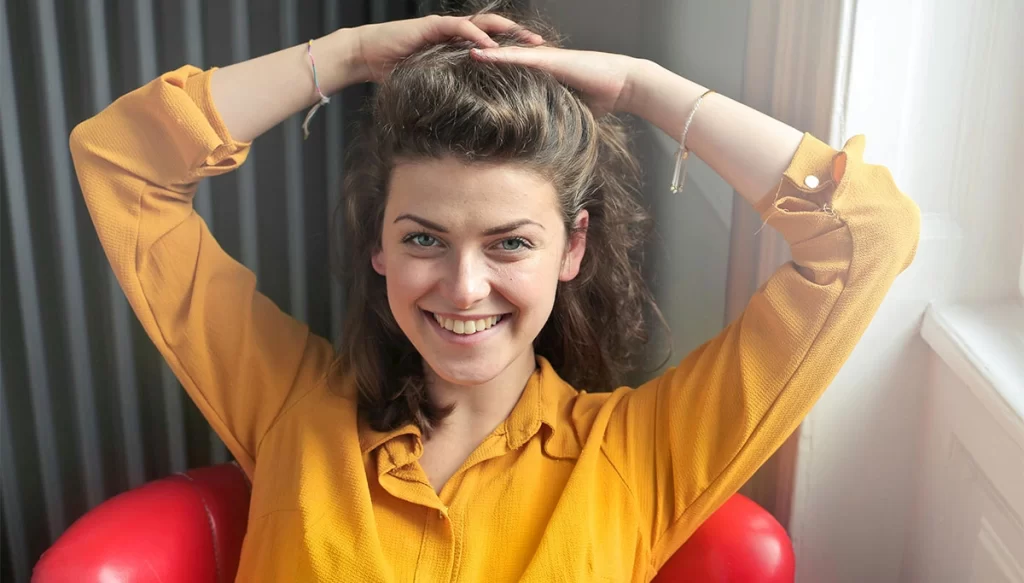 woman in a chair with her hair up smiling 