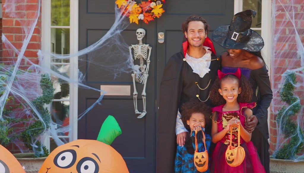 Family infront of home with two kids in halloween costumes